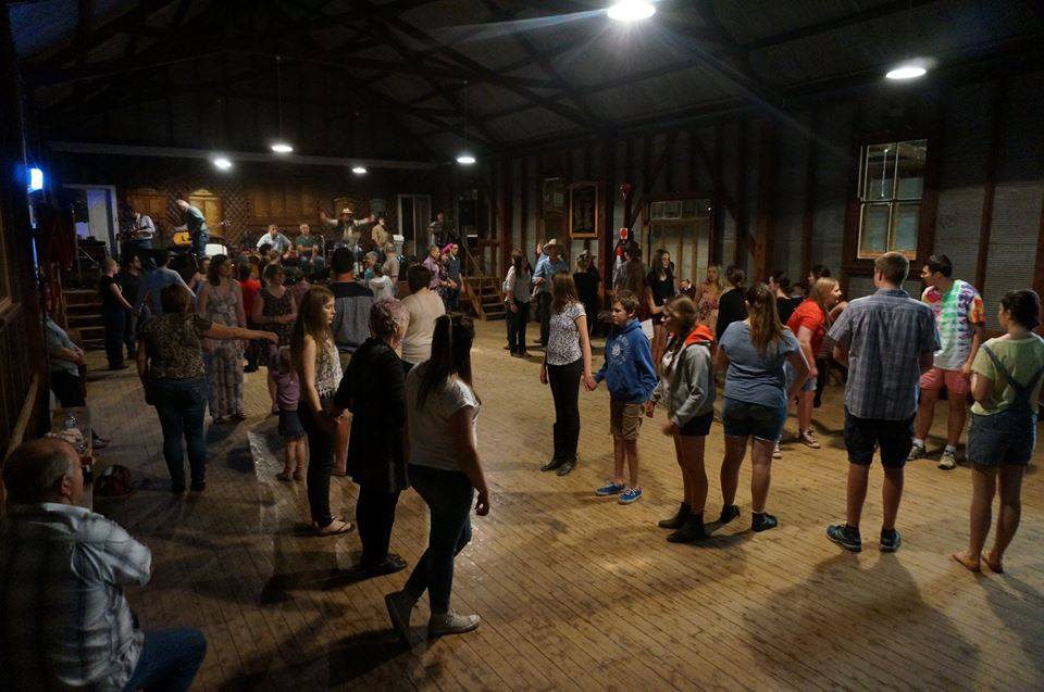 A crowd of people dance in front of the stage where Tin Shed Rattlers are playing